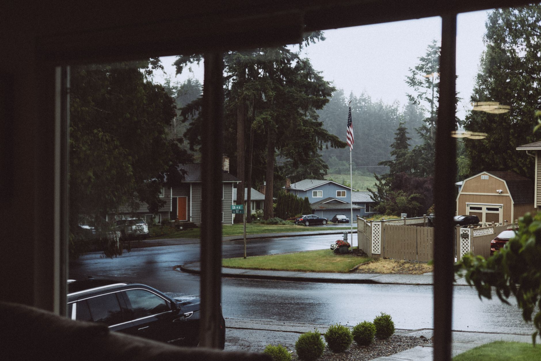 Rain falling on a quiet suburban street seen through a window