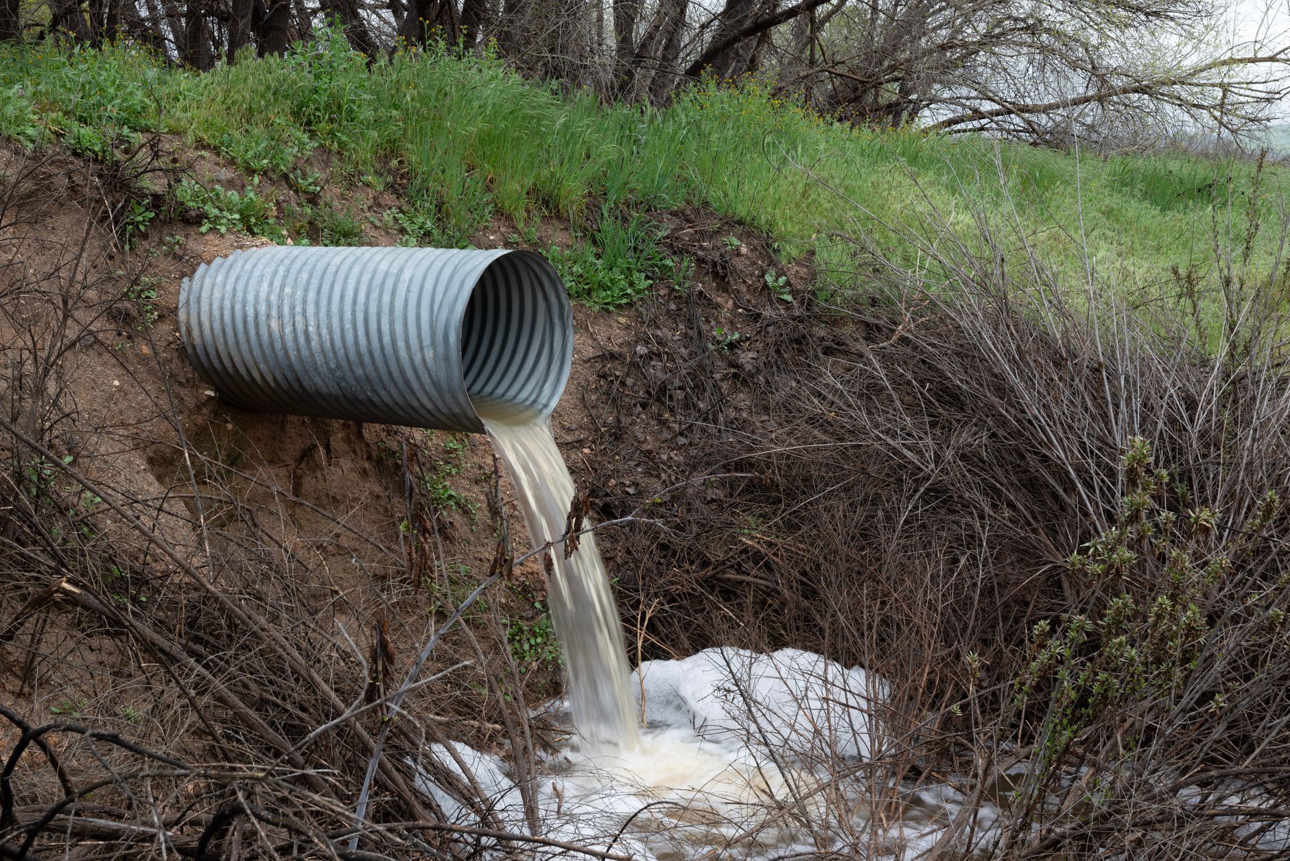 Corrugated drainage pipe discharging stormwater into a ravine